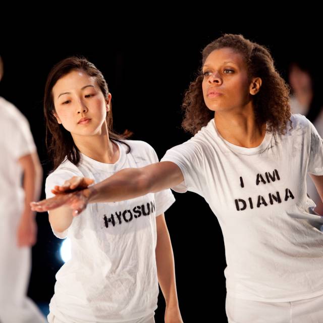 two women reach out one arm with hands overlapping
