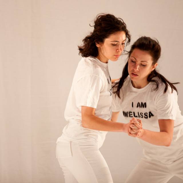 two women clasp hands while embracing