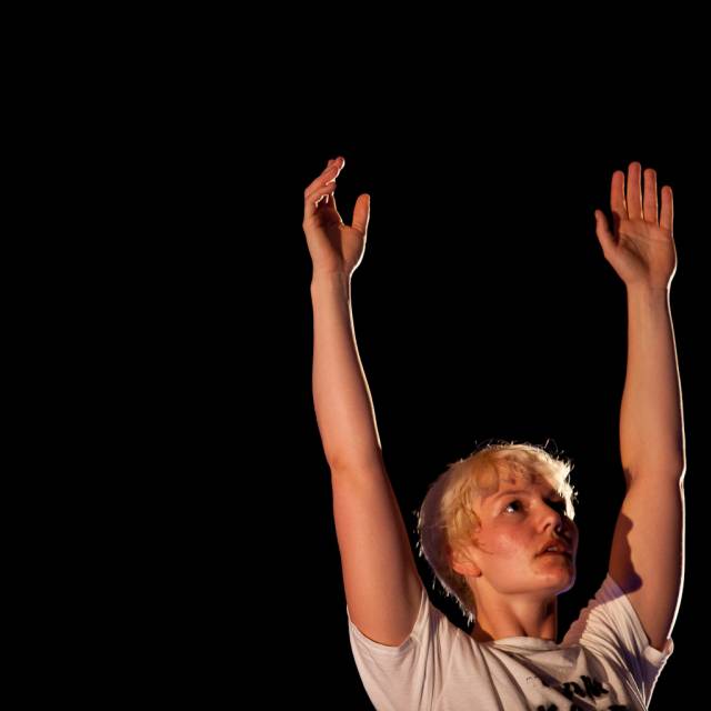a woman looks upward with her arms raised