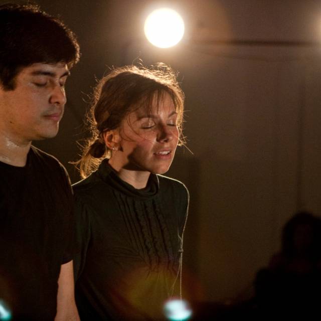a man and woman stand shoulder to shoulder with their eyes closed