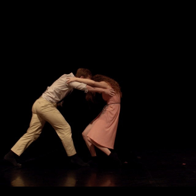 a man and woman face off, their arms on each other's shoulders