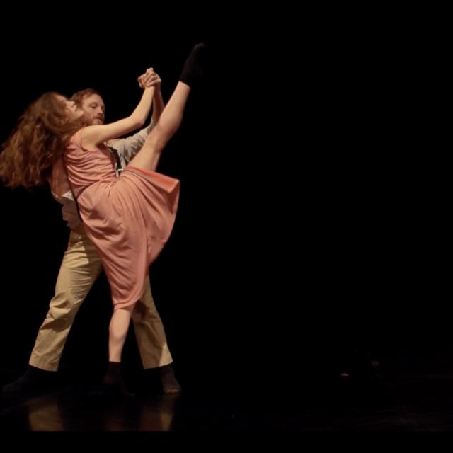 a man and woman partner while the woman kicks her leg high