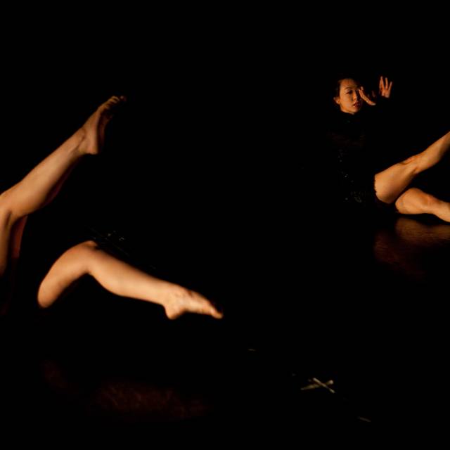 two figures sit with one leg floating in the air