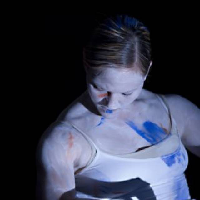 woman painted in white with blue paint splotches on her