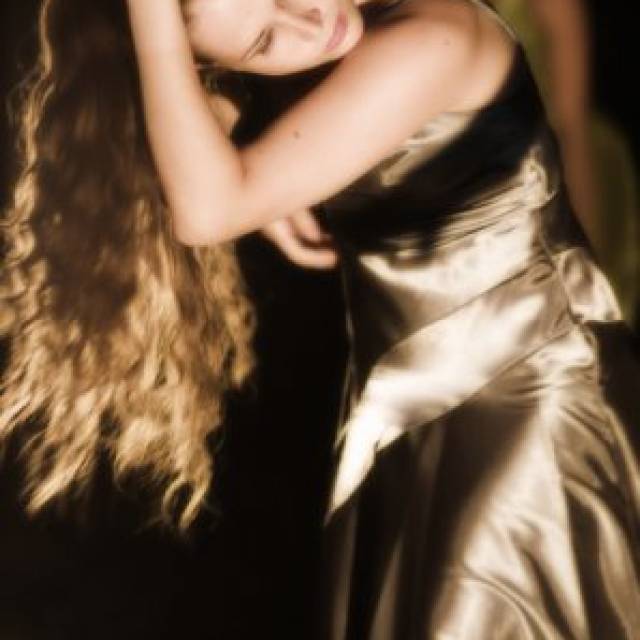 a woman captured in motion & wearing a gold dress 