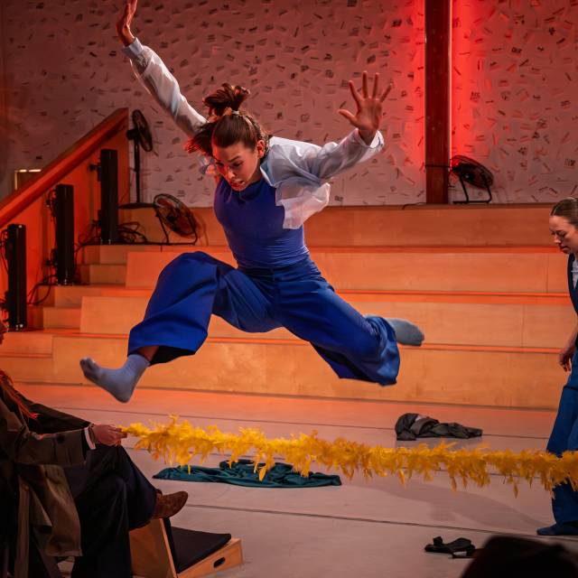 a dancer jumps over a feather boa obstacle
